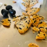 sablés au beurre au parmesan et aux olives renversés sur un plan de travail avec de la farine et des olives